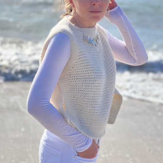 Frau trägt handgestrickten KOSI TOP am Strand, ohne sichtbare Nähte, perfekt für DIY-Kultur.