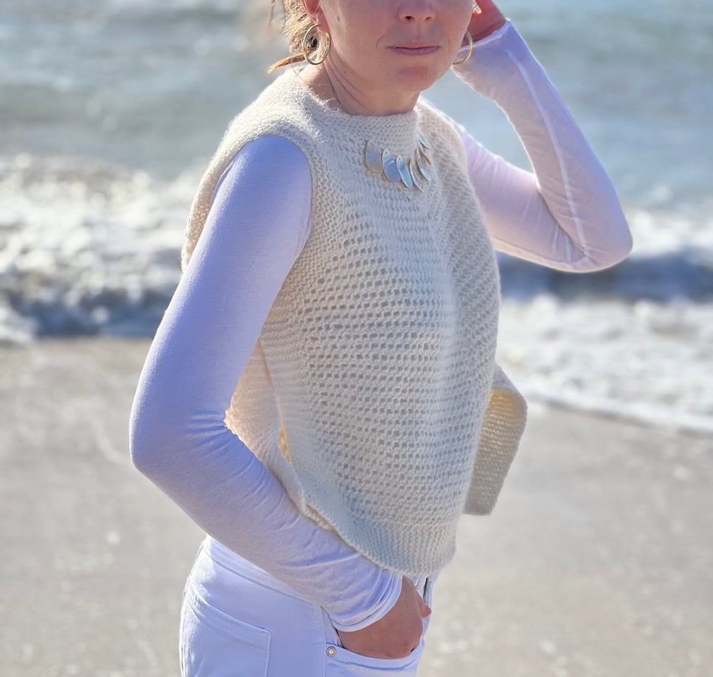 Frau trägt handgestrickten KOSI TOP am Strand, ohne sichtbare Nähte, perfekt für DIY-Kultur.
