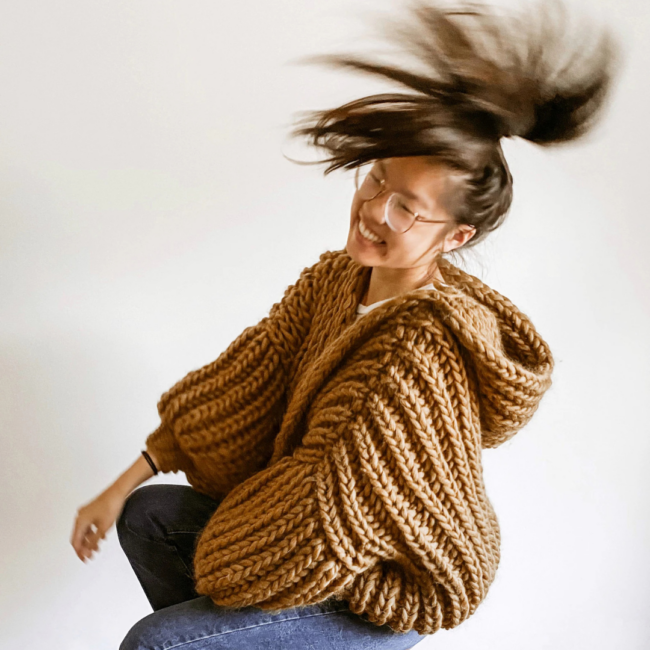 Junge Frau trägt den MARSHMALLOW Cardigan von BrendaMadeThis, einen oversized chunky Cardigan mit Kapuze in hellbraun.