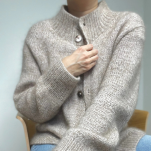 Junge Frau trägt SOFT LOOP Cardigan von Casual Knits Studio, einen weichen Cardigan mit größeren Knöpfen und feinen Details an Kragen und Ärmeln. Zu sehen ist der Ausschnitt von Hals bis Hüfte.