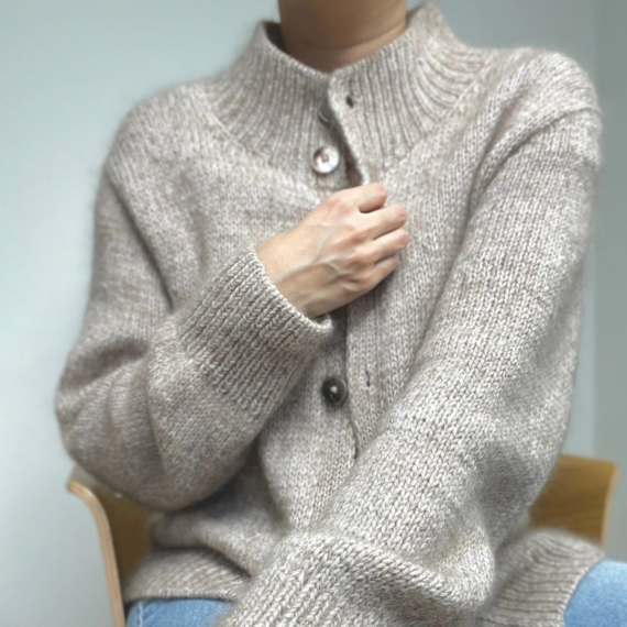 Junge Frau trägt SOFT LOOP Cardigan von Casual Knits Studio, einen weichen Cardigan mit größeren Knöpfen und feinen Details an Kragen und Ärmeln. Zu sehen ist der Ausschnitt von Hals bis Hüfte.